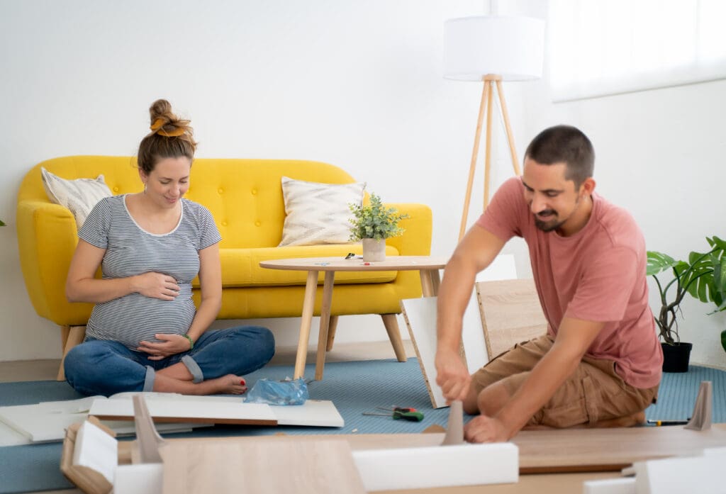Pregnant couple assembling furniture arranging the house waiting for the arrival of a new baby.
