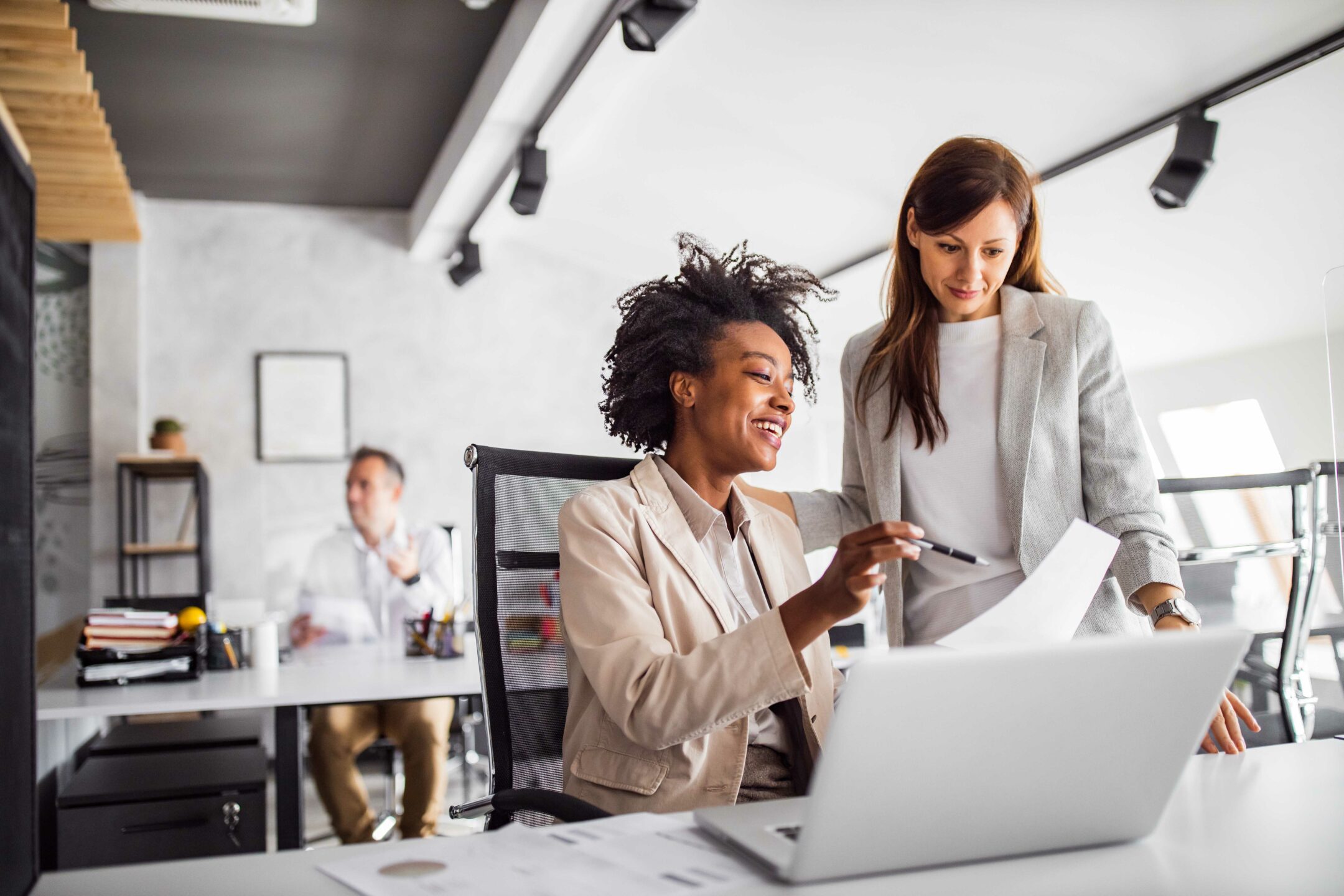 Two brunette business woman, talking, advising each other.