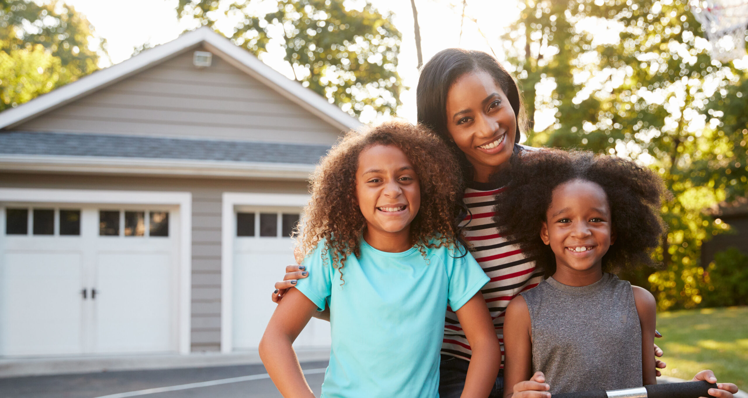 Mortgages. Mother With Children Riding Scooters On Driveway At Home